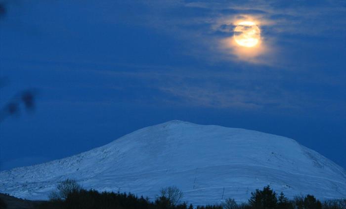 Snow covered mountain Moel Hebog under the moonlight. An area of Dark Skies